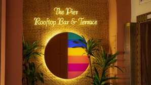 An interior view of The Pier Rooftop Bar & Terrace with a circular mirror and two potted plants.