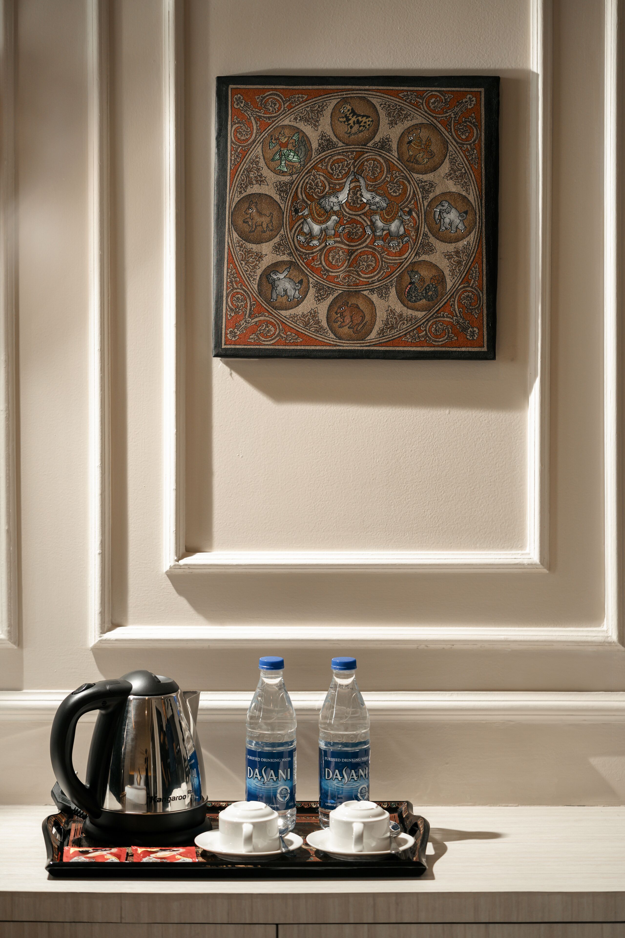 A tray with a coffee pot, two water bottles, and two cups on a table.