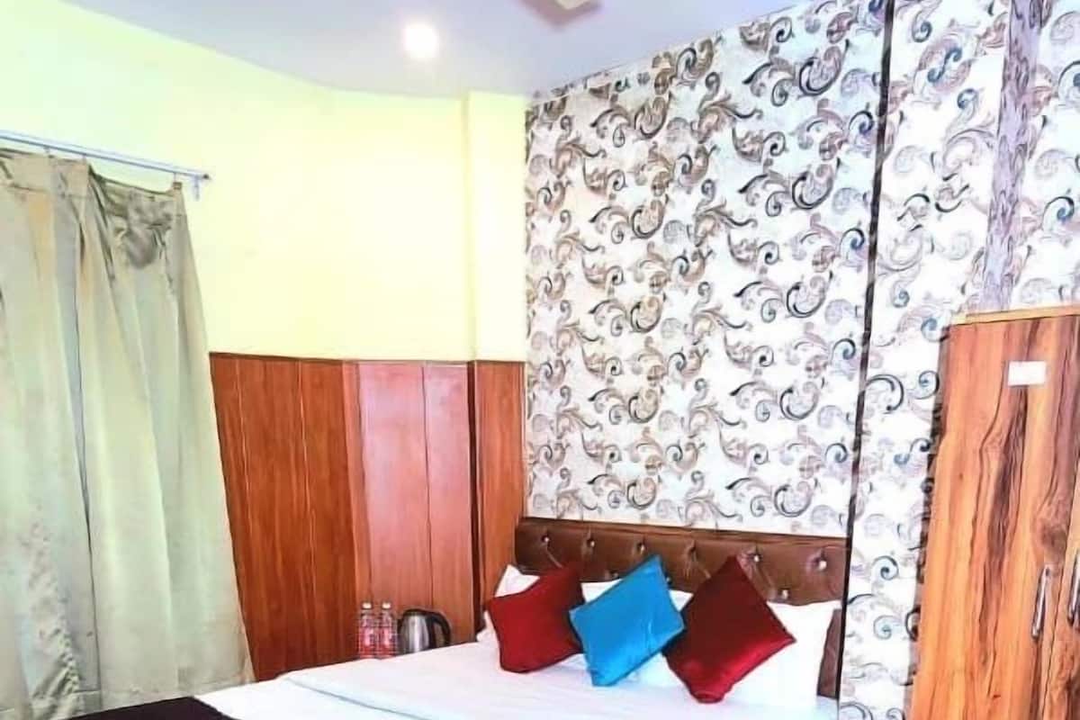A hotel room with a bed, a ceiling fan, a wardrobe, and a bathroom chair.