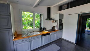 A modern kitchen with grey cabinets, a wooden countertop, a black range hood, a microwave, and a coffee maker. - Country house with garden ★ free pool and jacuzzi ★ Cévennes (Cros)