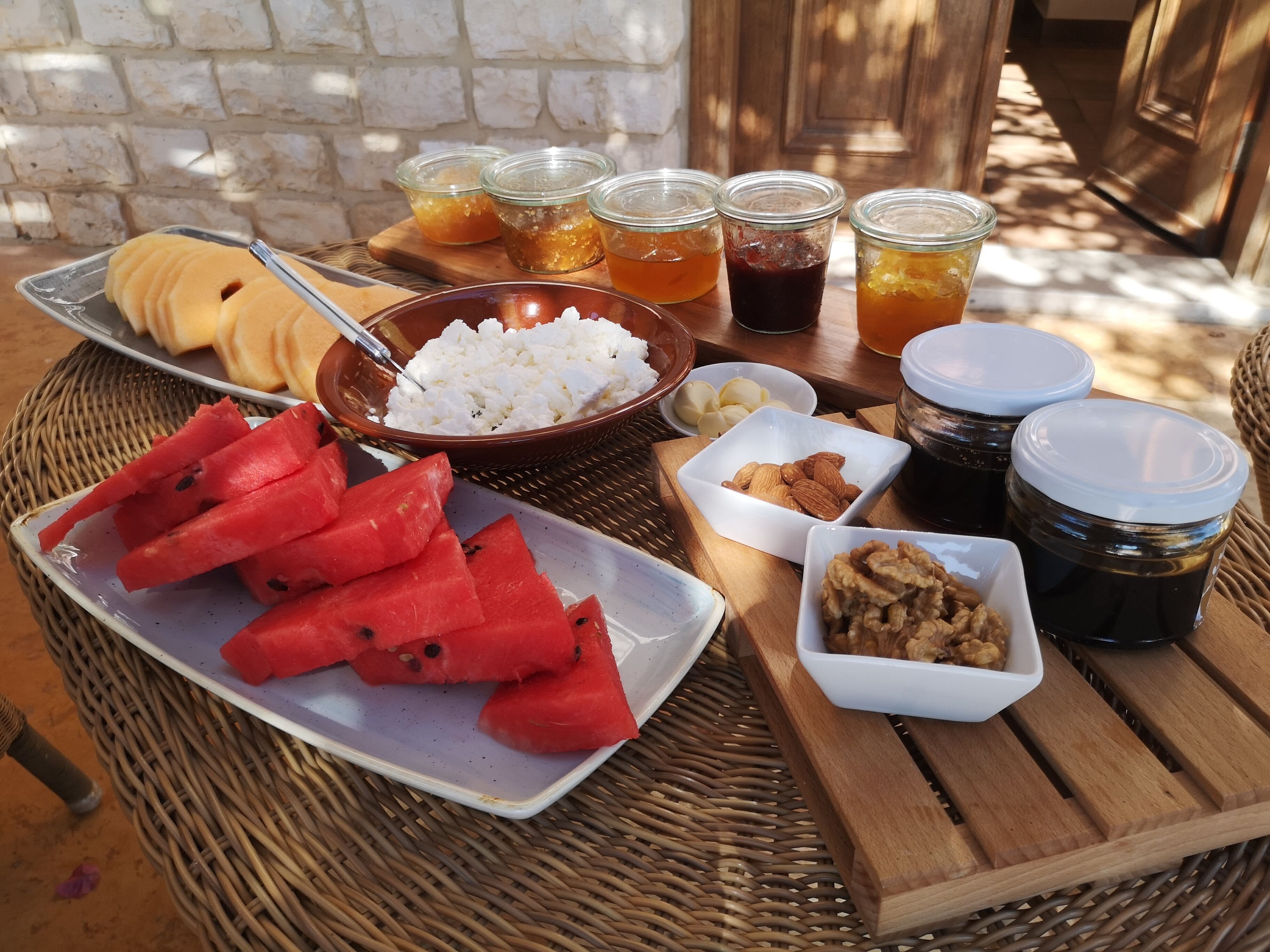 A table with various food items including watermelon, nuts, and jars of preserves.