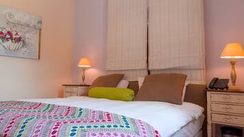 Una habitación de hotel con una cama, dos mesitas de noche, una lámpara en cada mesita y un cuadro en la pared.