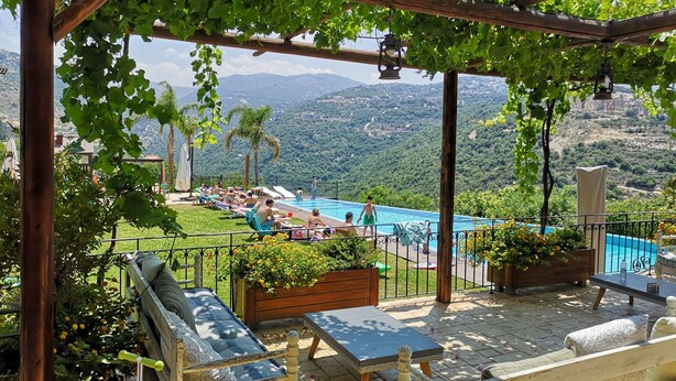 Zona de piscina con pérgola, asientos y vistas a un paisaje montañoso.