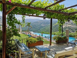 Zona de piscina con pérgola, asientos y vistas a un paisaje montañoso.