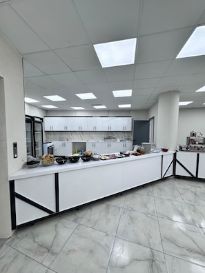 A modern kitchen with white cabinets, a marble countertop, and a central island with food items.