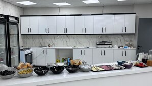 Une cuisine moderne avec des meubles blancs, un pare-feu en marbre et un îlot central agrémenté de différents bols et ustensiles.