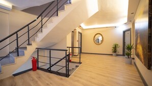 Un intérieur spacieux avec un escalier, un extincteur, un miroir et des plantes en pot.