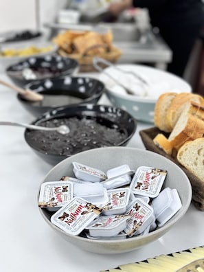 A table with various food items including a bowl of ice cream, a bowl of nuts, and a plate of bread.