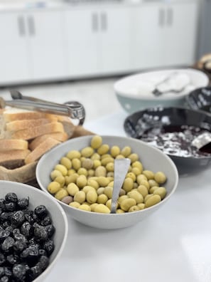 A table with various food items including olives, bread, and a bowl of chickpeas.