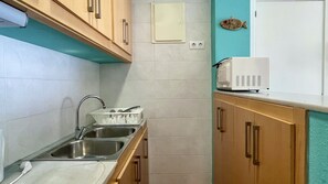 A kitchen with a sink, a microwave, wooden cabinets, and a fish decoration on the wall.