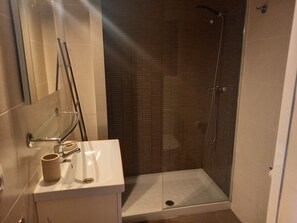 A bathroom with a shower, a sink, and a mirror.