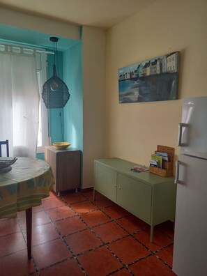 A kitchen with a dining table, a hanging light fixture, a cabinet, and a painting on the wall. - PUIG SUREDA 36 2-1 (L'Escala)