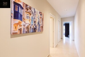 A hallway with a large, colorful mural on the wall, a clean, tiled floor, and a door leading to another room.