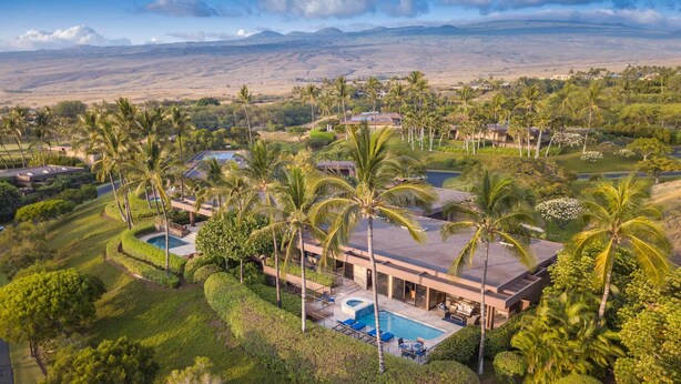Un resort grande y moderno con varias construcciones, piscina y exuberante vegetación.