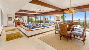 Un amplio salón con un gran ventanal, una mesa de comedor con sillas y un jarrón decorativo sobre un aparador.