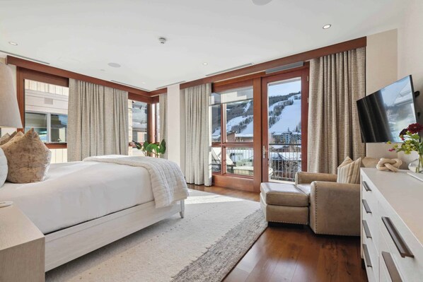 Une chambre d’hôtel moderne dotée d’un grand lit, d’un canapé, d’une télévision et offrant une vue sur un paysage enneigé.