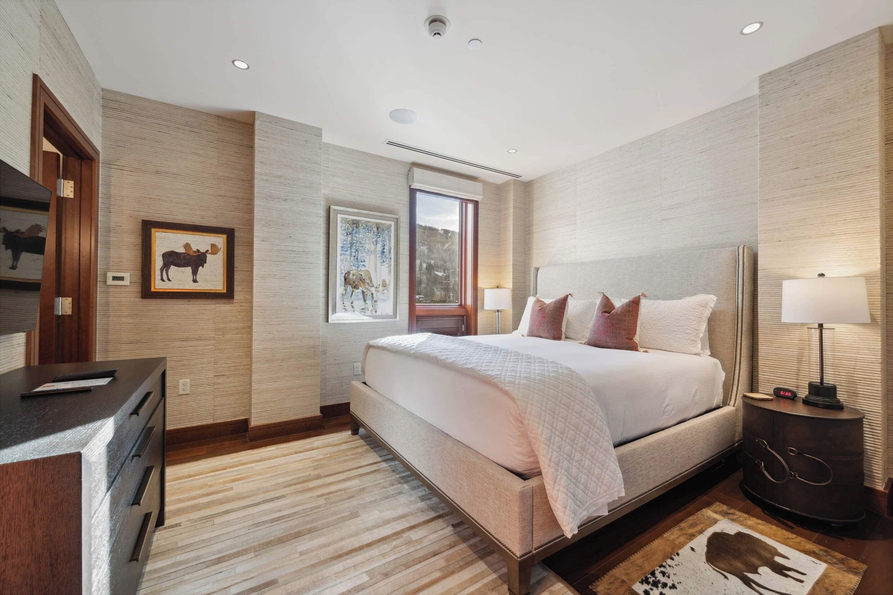 A modern bedroom with a large bed, a desk, and a nightstand.
