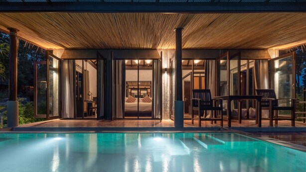 A modern house with a swimming pool, covered patio, and large glass doors leading to a bedroom. - Phapok Eco Resort (Suan Phueng)