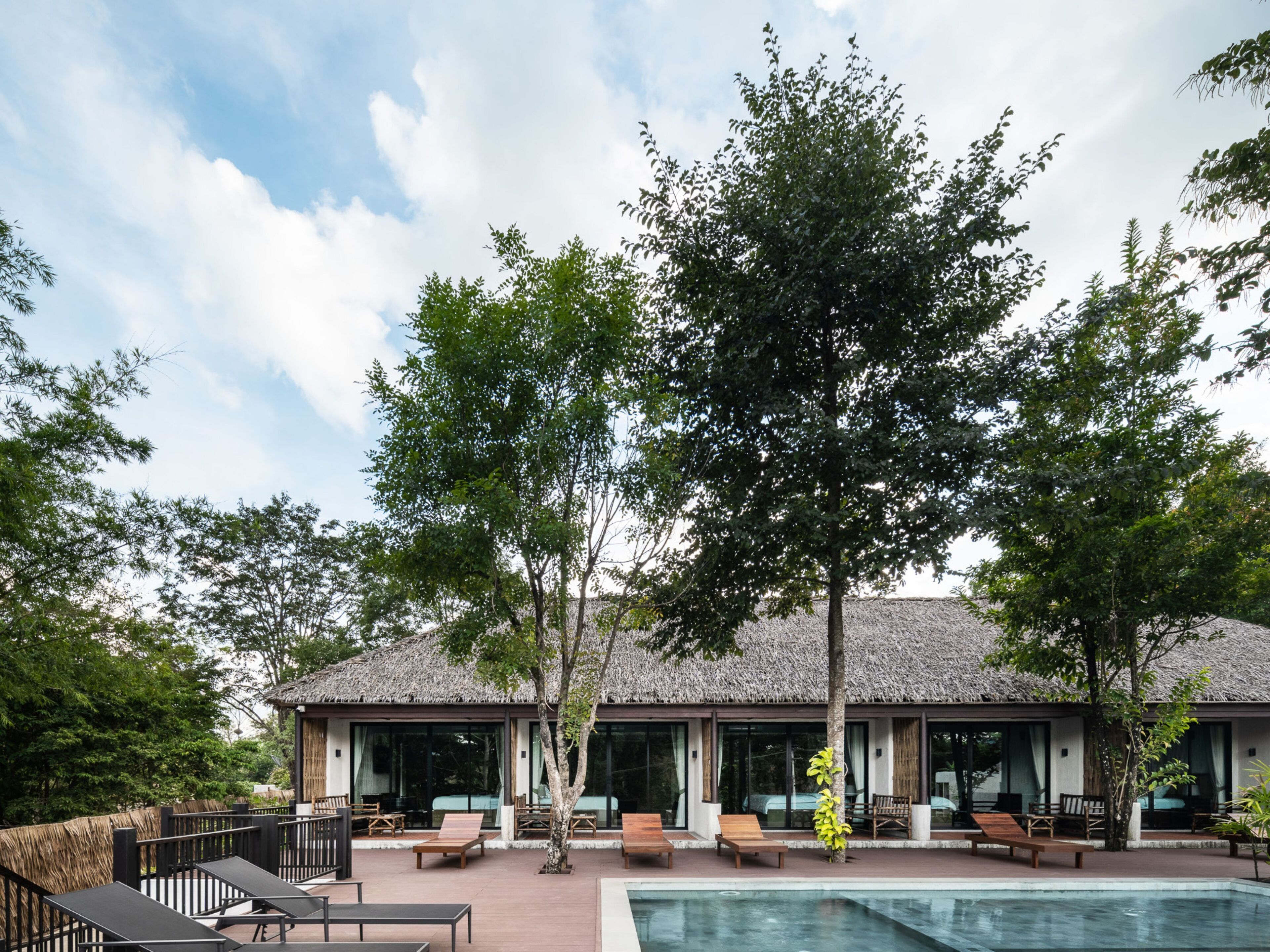 A resort with a pool, lounge chairs, and a thatched-roof building.