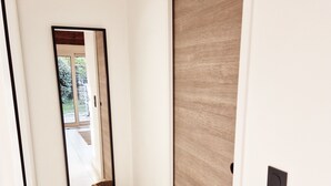 A hallway with a wooden door, a mirror, and a woven basket on the floor. - A Casuccia di Mammò (Oletta)