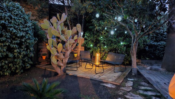 A patio area with a cactus, chairs, a table, and string lights. - A Casuccia di Mammò (Oletta)