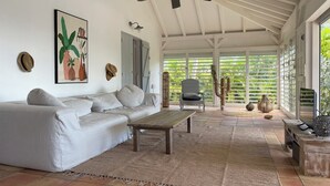 Un salon spacieux avec un canapé blanc, une table basse en bois et un ventilateur de plafond.