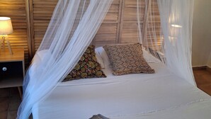 Un lit à baldaquin, des oreillers à motifs et une serviette roulée décorée de fleurs.