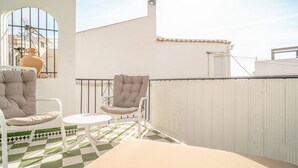 A rooftop terrace with two cushioned chairs, a small round table, and a checkered floor. - Holiday Home "Casa Colibri 2 Beach" with Shared Pool & Wi-Fi (Nerja)