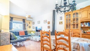 A cozy living room with a sofa, dining table, chairs, and a chandelier. - Holiday Home "Casa Colibri 2 Beach" with Shared Pool & Wi-Fi (Nerja)