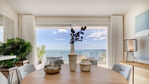 Un coin repas avec une table ronde, deux vases et une vue sur l’océan.