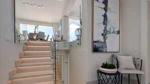 Un intérieur moderne avec un escalier, un coin repas et un grand tableau abstrait.