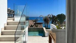 Un balcon moderne avec une balustrade en verre, une piscine et une vue sur la mer.