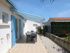 Une terrasse avec une table et des chaises, une porte bleue et un mur blanc.