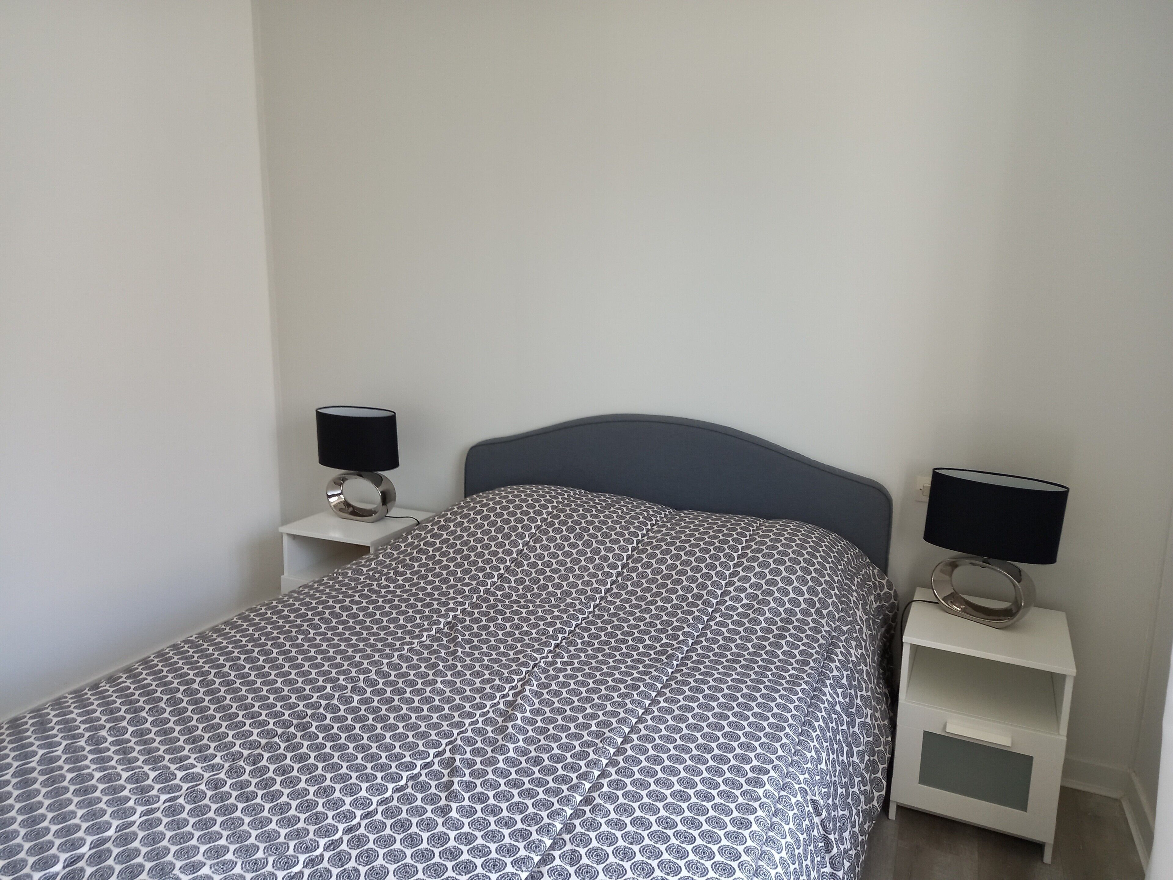 Una camera da letto con un letto, due comodini con lampade e una coperta a motivi decorativi.