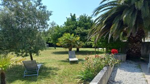 A garden with two lounge chairs, a palm tree, and a variety of plants. - Holiday Home 'Picotelle' with Private Terrace, Private Garden and Wi-Fi (Le Château d'Oléron)