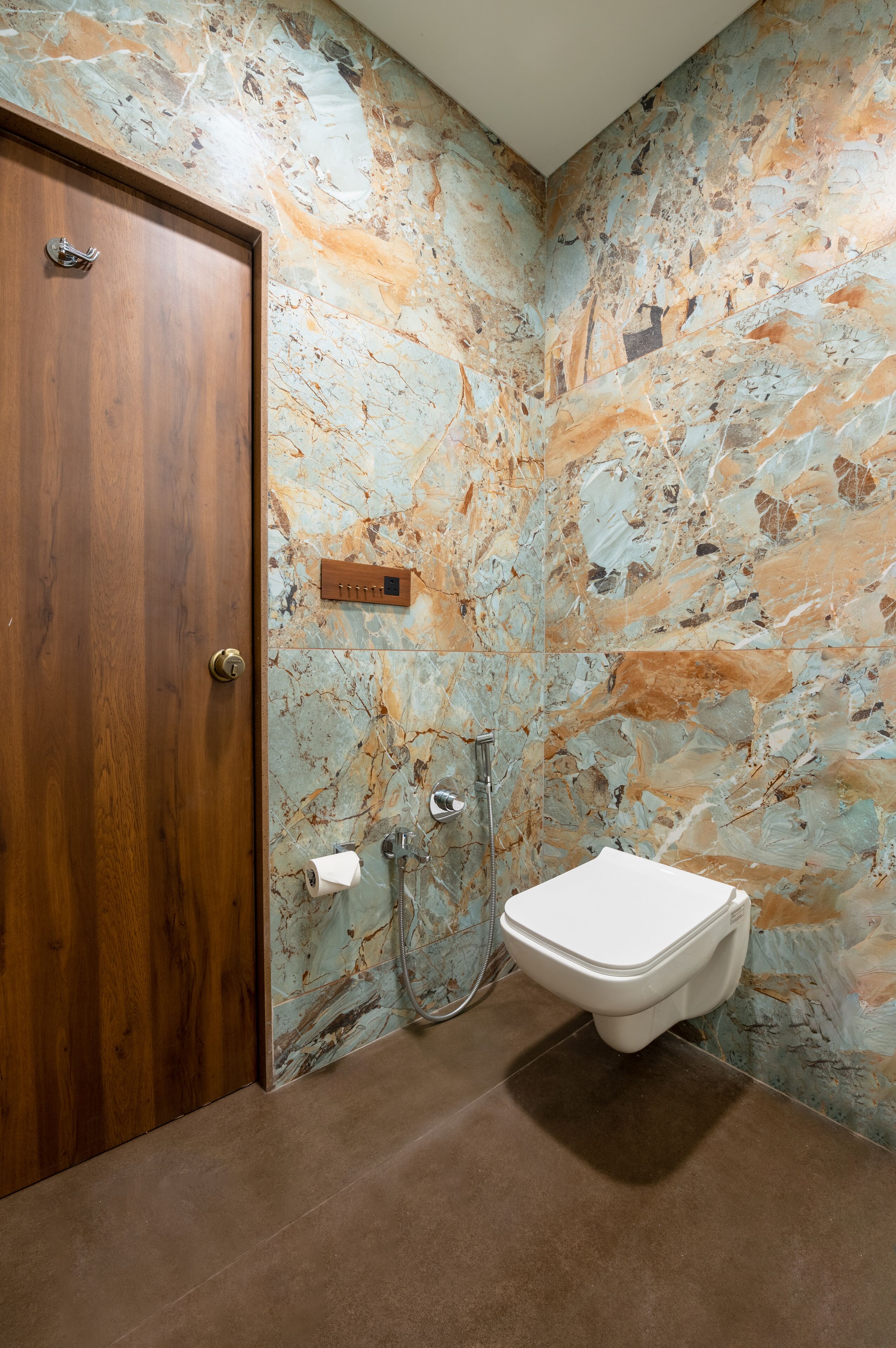 Ein Badezimmer mit Holztür, Marmorwand, Toilette und Dusche.