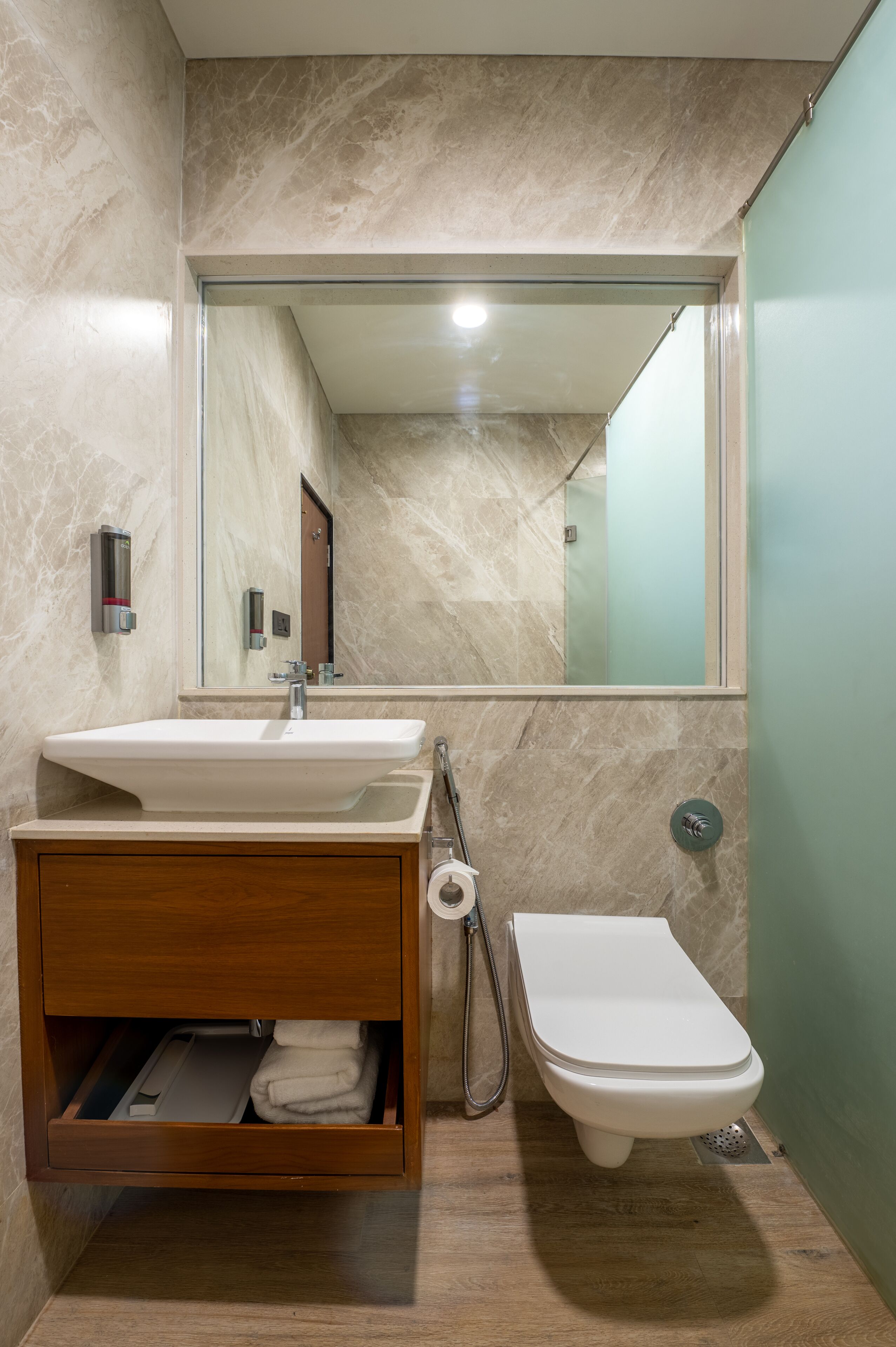 A modern bathroom with a marble sink, wooden vanity, and a toilet.