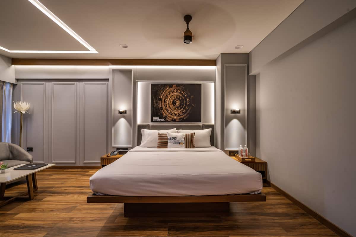 A modern bedroom with a large bed, bedside lamps, a wall-mounted artwork, and a wooden floor.