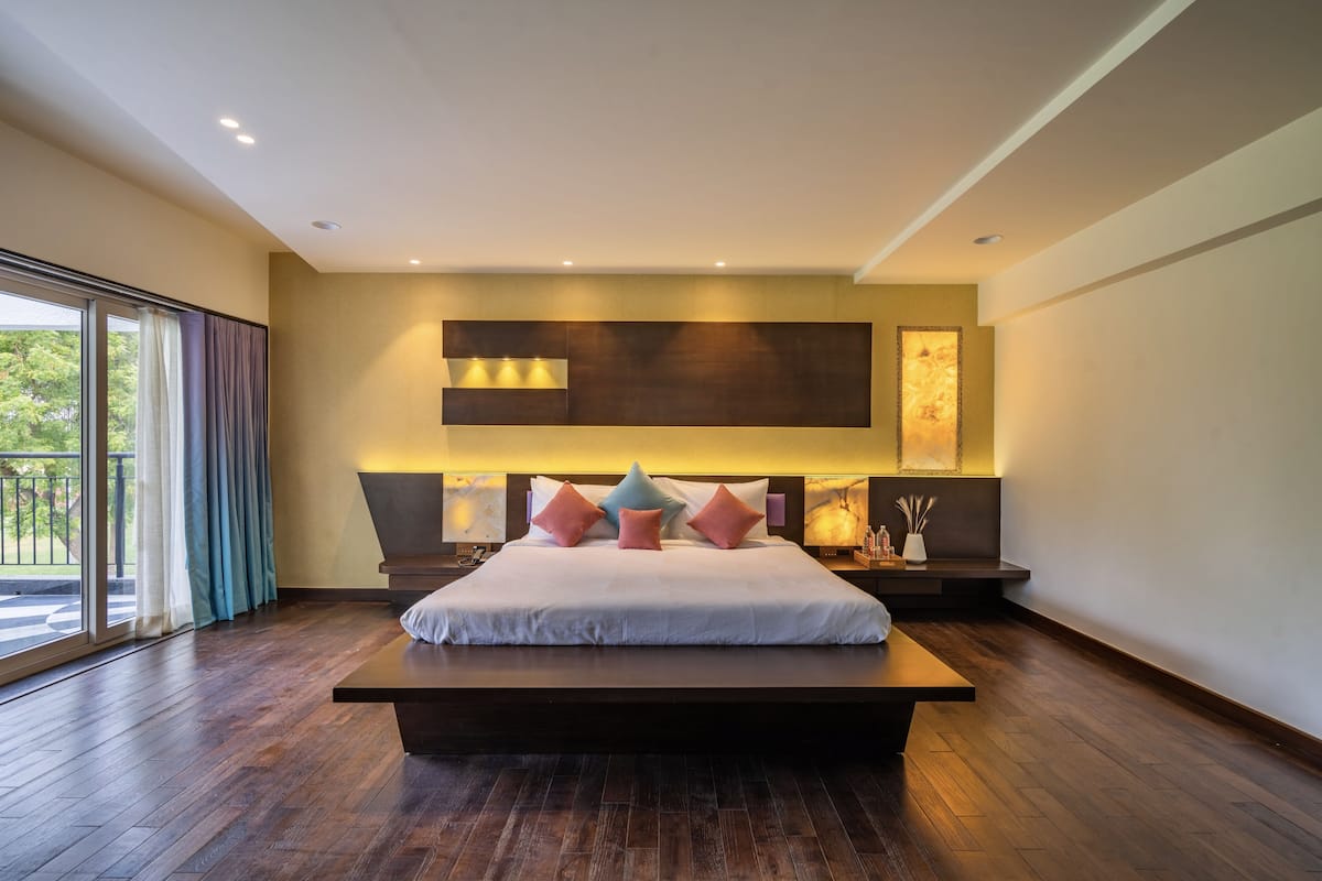 A modern bedroom with a large bed, a view to the outdoors, and a minimalist design.