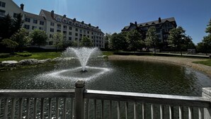 En springvand i en park med klar himmel og bygninger i baggrunden.