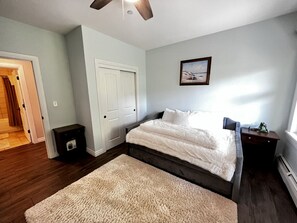 A bedroom with a bed, a nightstand, a door, and a window.