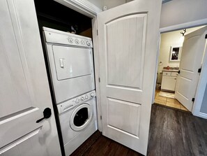 A laundry room with a washer and dryer, wooden flooring, and white doors.
