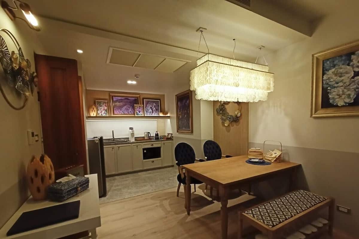 Een eethoek met een houten tafel en stoelen, een bankje en een kroonluchter.