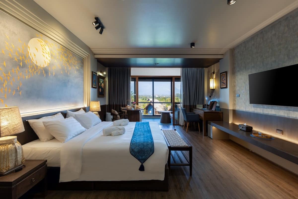 Een hotelkamer met een groot bed, een bureau, een televisie en een balkon met uitzicht.