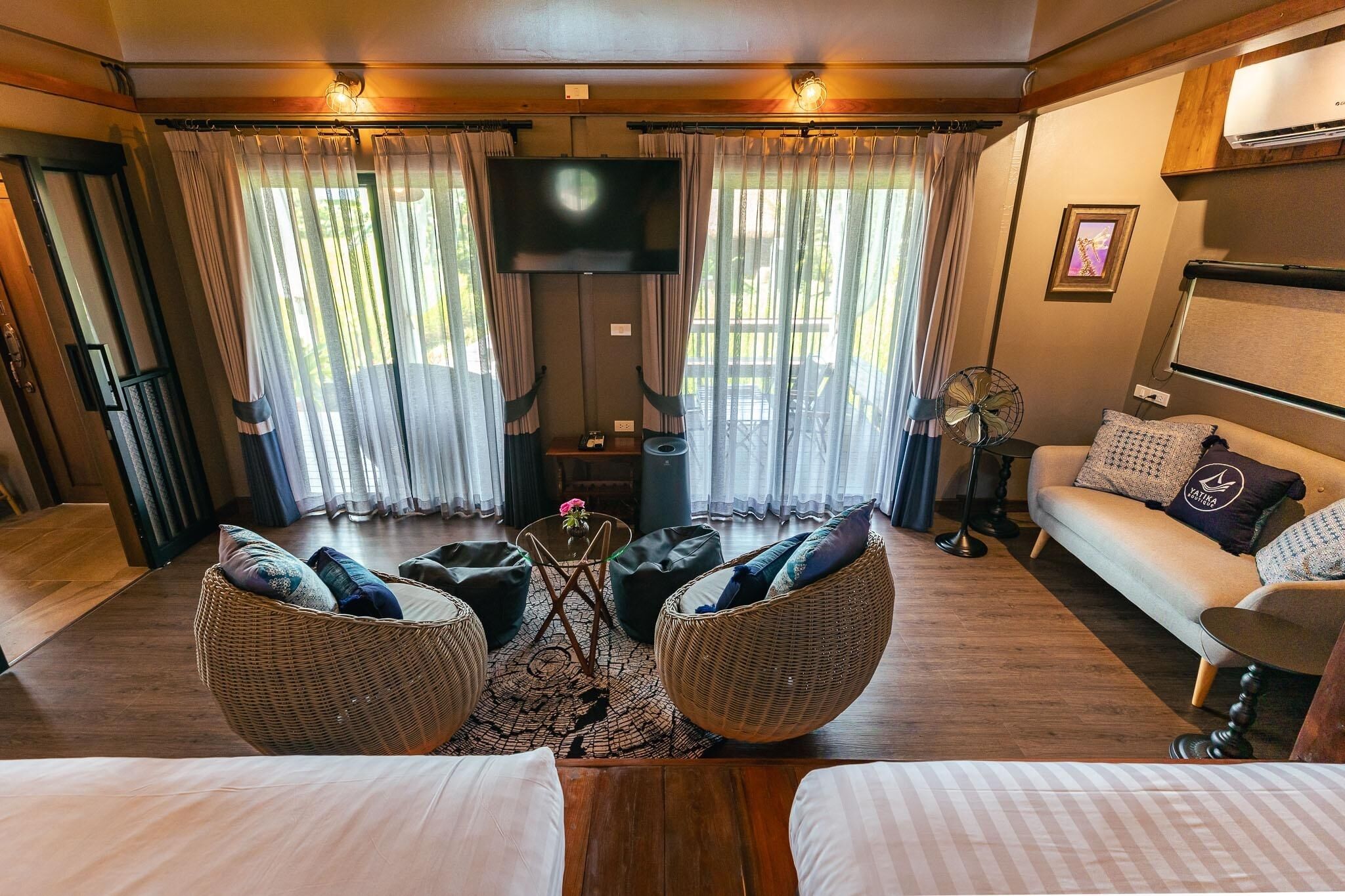 A cozy living area with wicker furniture, a flat-screen TV, and a sofa with decorative pillows.
