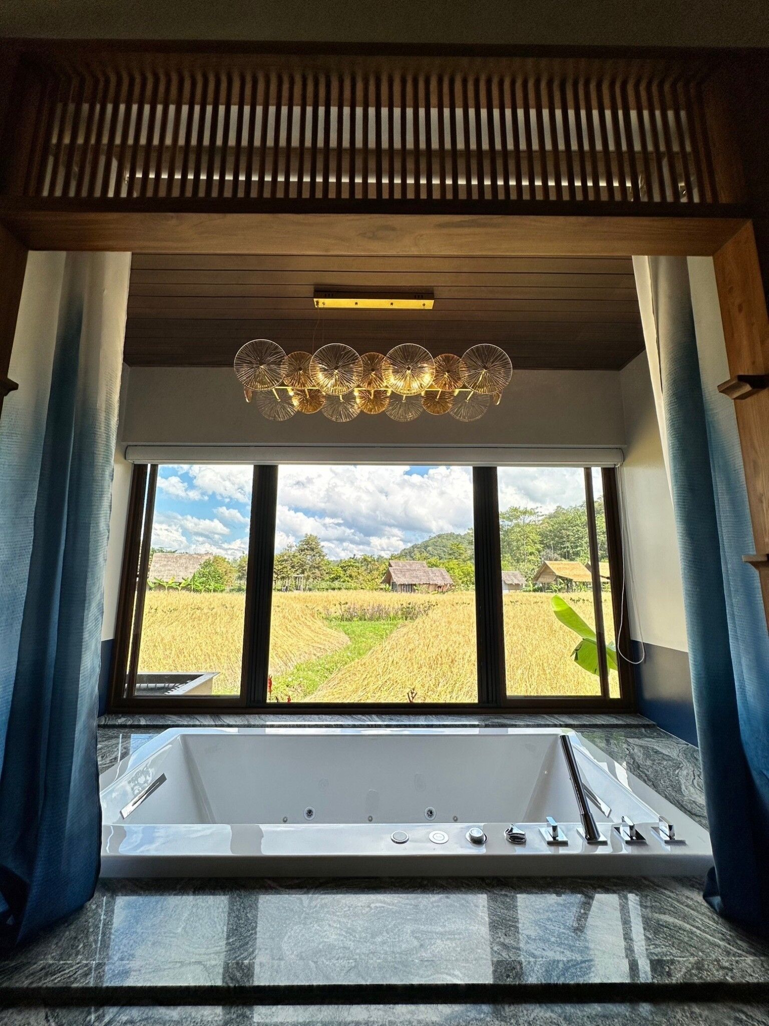 Un baño con una ventana grande, una bañera y un aplique de techo.