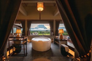 A luxurious bathroom with a large bathtub, a view of a mountainous landscape, and a modern design. - Yatika Boutique Resort (Chiang Dao)
