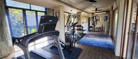 A home gym with treadmills, weight machines, and a ceiling fan.