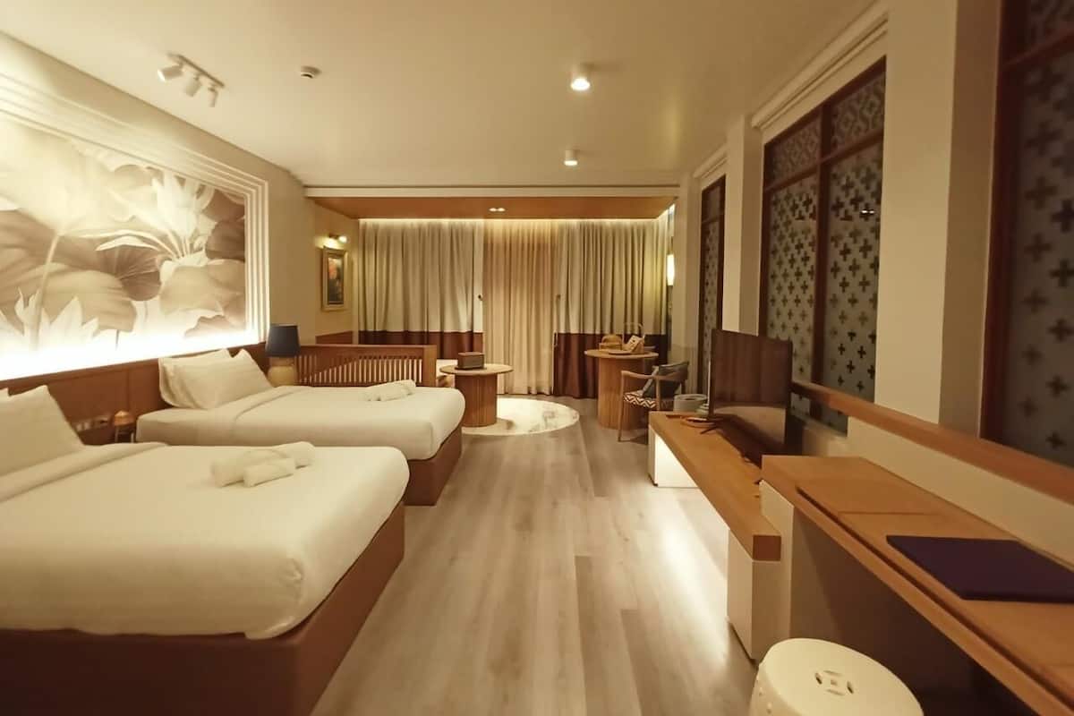 Een hotelkamer met twee bedden, een bureau, een stoel, een klein tafeltje en een televisie.