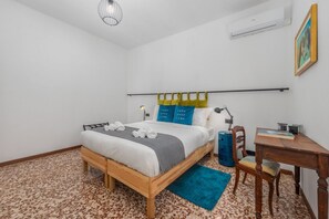 A bedroom with a wooden bed, a desk, a chair, a blue rug, and a wall-mounted air conditioner. - Vivi Il Lago - Lake View (Cernobbio)